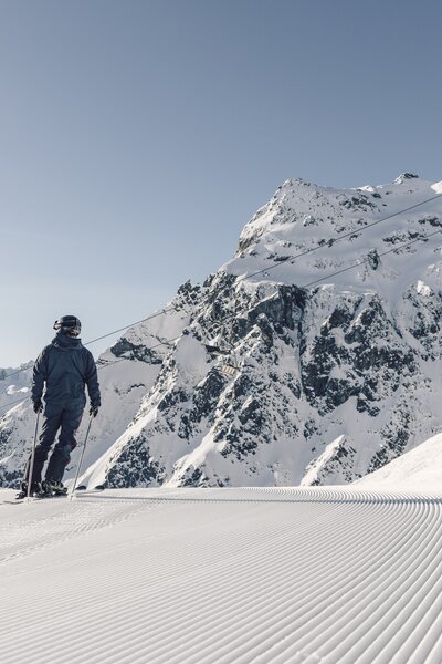 Skifahren vor der imposanten Madrisa in Gargellen | © Gargellner Bergbahnen, Daniel Zangerl Ein Skifahrer steht auf einer frisch präparierten Piste in Gargellen mit Blick auf verschneite Berge und Sessellift. | © Gargellner Bergbahnen, Daniel Zangerl