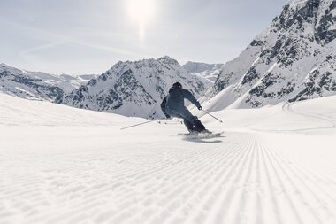 Skifahrer fährt in Schwüngen eine frisch präparierte Piste in Gargellen hinunter, verschneite Bergkulisse im Hintergrund. | © Gargellner Bergbahnen GmbH & Co KG, Daniel Zangerl