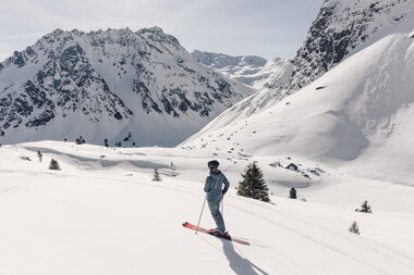 Skifahrer steht im verschneiten Gelände in Gargellen am Fuße des imposanten Berges Madrisa und blickt auf die umliegenden Berggipfel. | © Gargellner Bergbahnen GmbH & Co KG, Daniel Zangerl