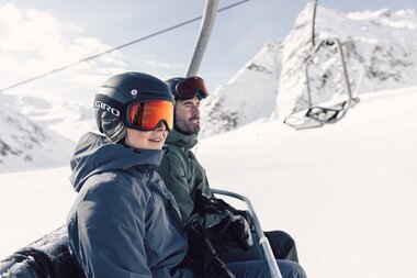 Nahaufnahme von zwei Skifahrern im Sessellift mit Helmen und Skibrillen auf dem Weg zum Gipfel. | © Gargellner Bergbahenn GmbH & Co KG, Daniel Zangerl