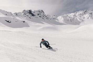 Skigenuss im Täli | © Gargellner Bergbahnen GmbH & CO KG, Daniel Zangerl Skifahrer in grüner Jacke fährt in tiefer Kurvenlage die Piste Täli in Gargellen, verschneite Hänge im Hintergrunnd. | © Gargellner Bergbahnen GmbH & CO KG, Daniel Zangerl