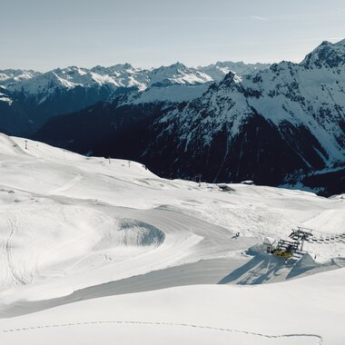 Luftaufnahme der verschneiten Skipisten von Gargellen mit präparierten Abfahrten im Vordergrund. Im Hintergrund sind schneebedeckte Bergketten und das Tal zu sehen. | © Gargellner Bergbahnen GmbH & Co KG, Daniel Zangerl