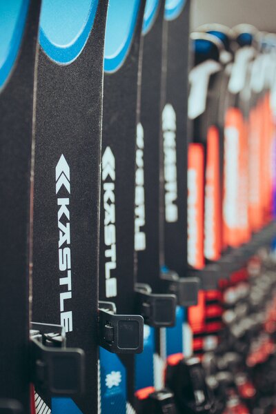 Mehrere Paar Ski der Marke Kästle stehen ordentlich in einer Reihe in einem Skiverleih. Die Vorderseiten der Ski in Blau, Schwarz und Rot sind deutlich zu erkennen. Der Hintergrund des Raums ist unscharf, wodurch der Fokus auf den Ski liegt. | © Gargellner Bergbahnen GmbH & Co KG, Christoph Schöch 