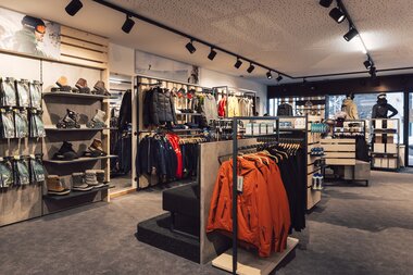 Übersichtlicher Innenraum eines Sportshops mit Regalen für Wintersportschuhe, Handschuhe und Accessoires sowie Kleiderständern mit Jacken und Hosen; die Verkaufsfläche ist modern gestaltet und gut ausgeleuchtet. | © Gargellner Bergbahnen GmbH & Co KG, Daniel Zangerl